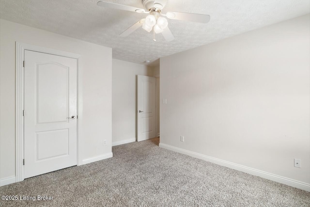 unfurnished bedroom featuring carpet, a textured ceiling, baseboards, and ceiling fan