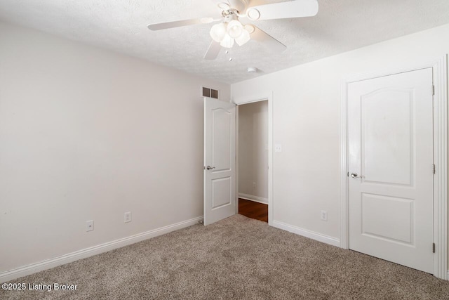 unfurnished bedroom featuring carpet floors, a textured ceiling, baseboards, and a ceiling fan