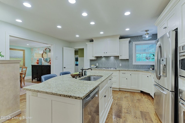 801 Shady Ln, Anchorage, KY 40223 - kitchen with stainless steel appliances, a sink, white cabinetry, light wood-style flooring, and a center island with sink