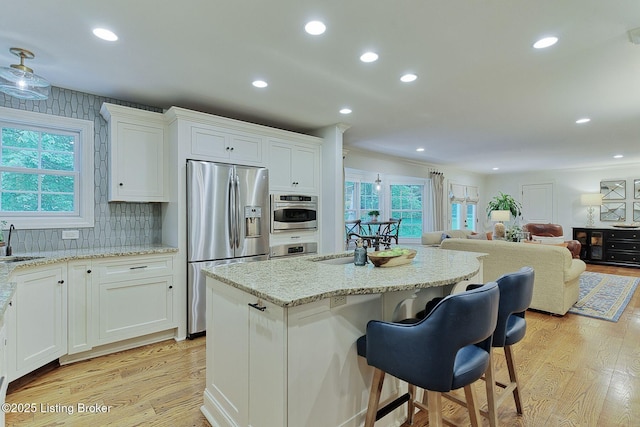 801 Shady Ln, Anchorage, KY 40223 - kitchen with stainless steel appliances, light wood-style floors, a sink, white cabinetry, and a center island with sink