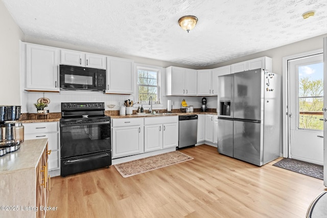 224 Murphy Ln, Bloomfield, KY 40008 - kitchen featuring black appliances, a sink, light wood-style flooring, white cabinetry, and a textured ceiling