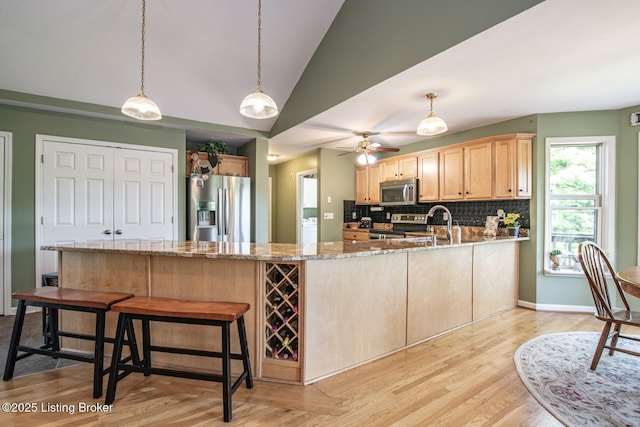 79 Ivy Ct, Brandenburg, KY 40108 - kitchen featuring appliances with stainless steel finishes, a peninsula, light brown cabinets, backsplash, and light stone counters