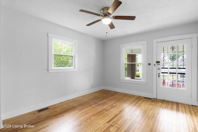 1011 Wetterau Ave, Louisville, KY 40217 - unfurnished room featuring plenty of natural light, light wood finished floors, ceiling fan, baseboards, and a textured ceiling