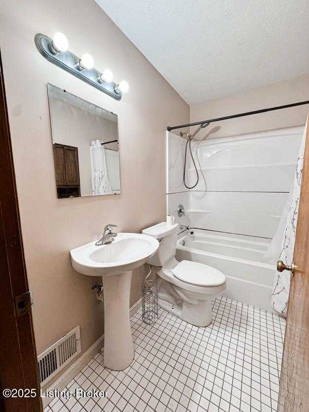 6302 Casper Dr, Louisville, KY 40258 - full bath with tile patterned floors, toilet, shower / bath combo with shower curtain, baseboards, and a textured ceiling