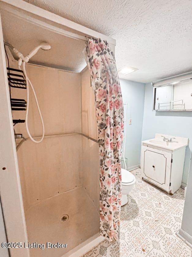 6302 Casper Dr, Louisville, KY 40258 - bathroom featuring a shower stall, a textured ceiling, toilet, vanity, and baseboards
