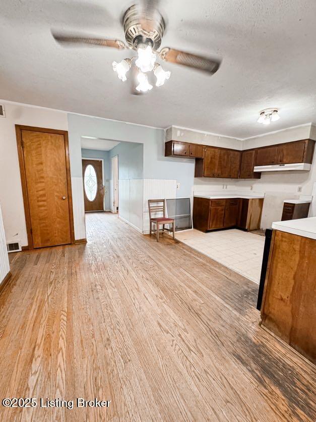 6302 Casper Dr, Louisville, KY 40258 - unfurnished living room with light wood-style floors, a ceiling fan, wainscoting, and a textured ceiling