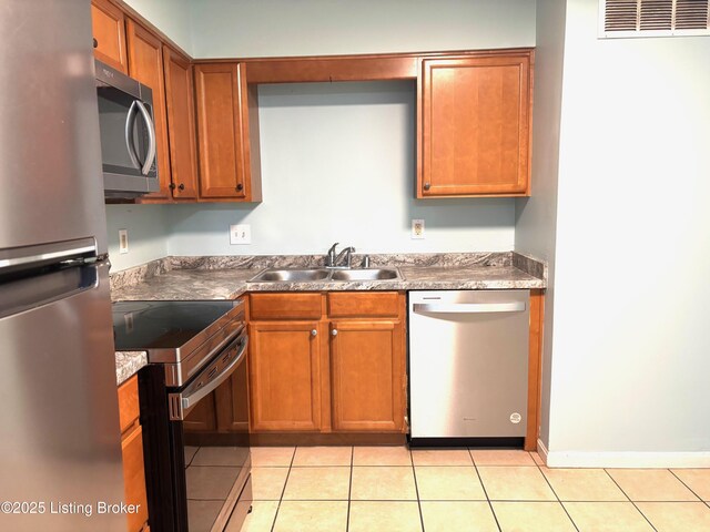 1513 La Fontenay Ct, Louisville, KY 40223 - kitchen featuring appliances with stainless steel finishes, a sink, light tile patterned flooring, brown cabinetry, and baseboards