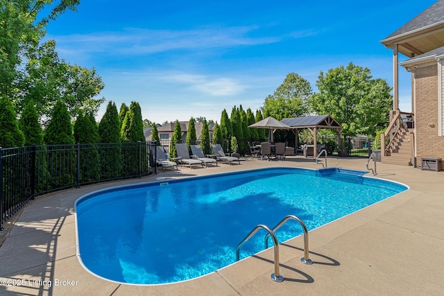 community pool with a patio, fence, stairway, and a gazebo