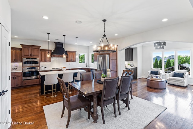 dining room featuring arched walkways, recessed lighting, dark wood-style flooring, and a chandelier