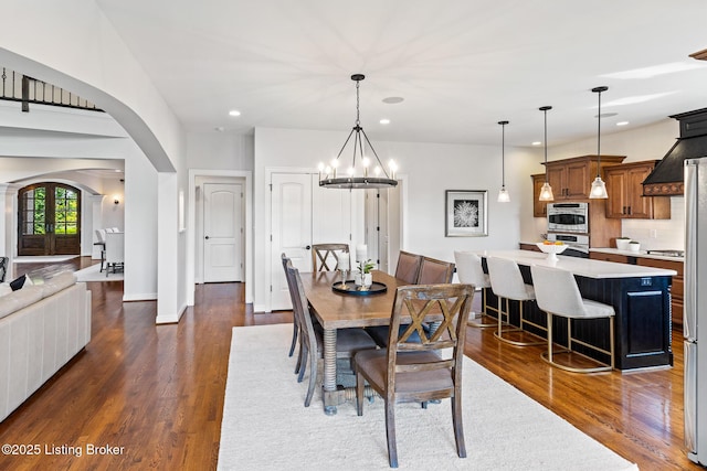 dining room featuring arched walkways, dark wood-style floors, recessed lighting, a chandelier, and baseboards