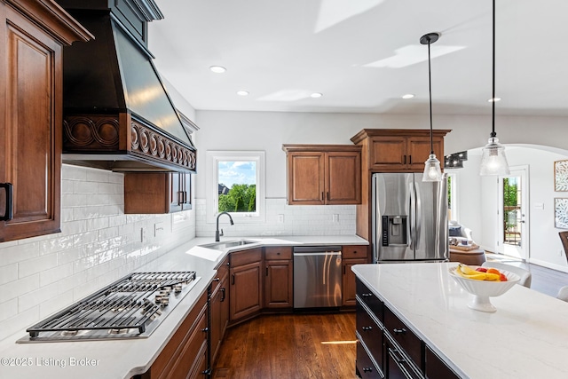 kitchen featuring stainless steel appliances, a sink, custom range hood, arched walkways, and recessed lighting