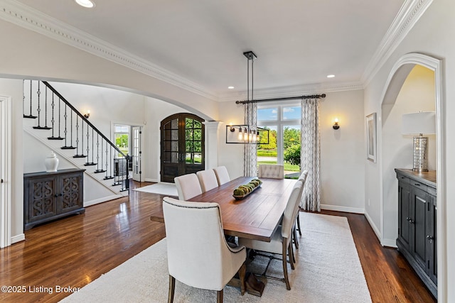 dining space featuring arched walkways, dark wood-style flooring, baseboards, recessed lighting, and crown molding