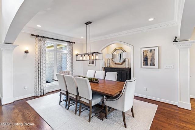 dining area featuring arched walkways, crown molding, baseboards, dark wood-type flooring, and recessed lighting