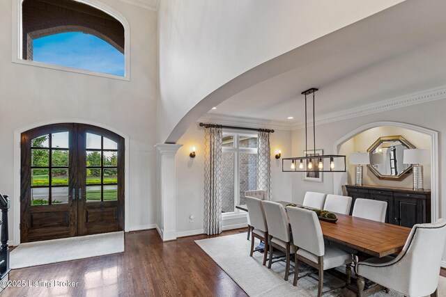 dining space featuring arched walkways, plenty of natural light, french doors, a chandelier, and ornamental molding