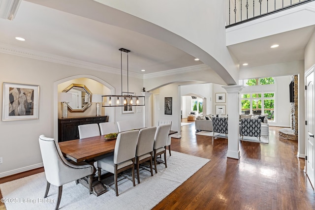 dining space with dark wood finished floors, crown molding, arched walkways, recessed lighting, and baseboards