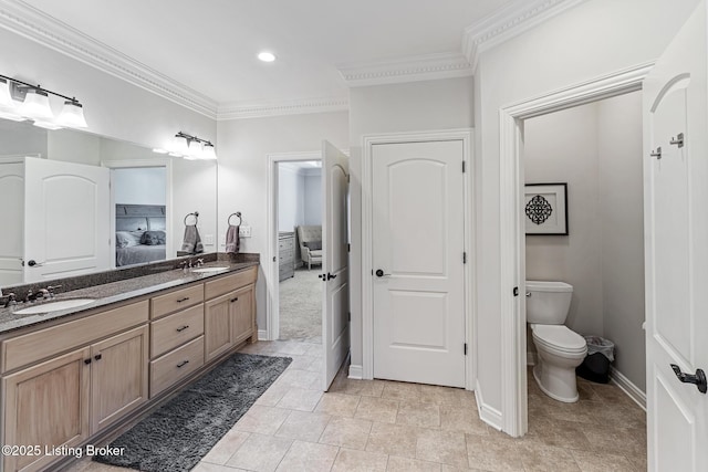 ensuite bathroom with crown molding, double vanity, toilet, baseboards, and recessed lighting
