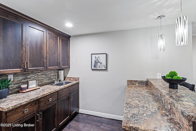 kitchen with baseboards, dark brown cabinetry, dark wood-style floors, decorative backsplash, and recessed lighting