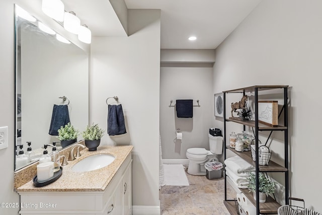 bathroom with toilet, baseboards, and vanity