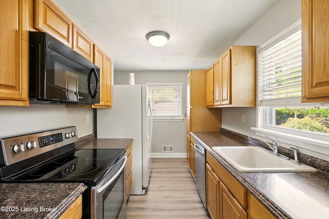 2410 Waco Ct, Louisville, KY 40216 - kitchen featuring stainless steel appliances, a sink, dark countertops, and light wood-style floors
