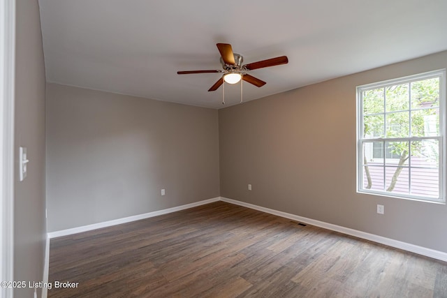 empty room with dark wood-style flooring, baseboards, and ceiling fan