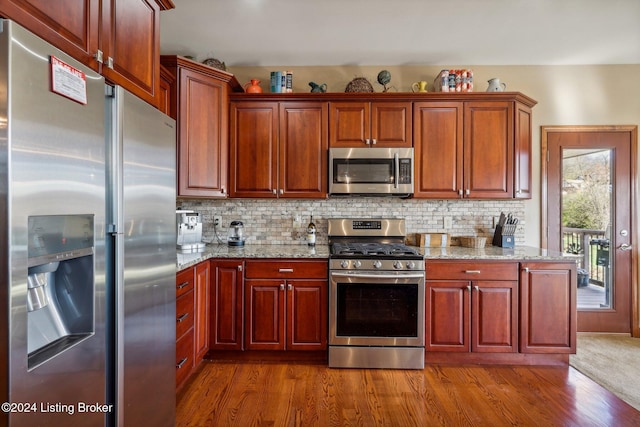 kitchen with appliances with stainless steel finishes, dark wood finished floors, and backsplash