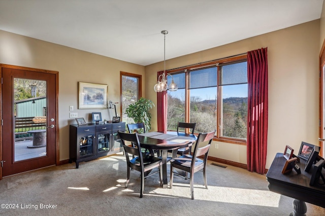 dining space with light colored carpet, plenty of natural light, and baseboards