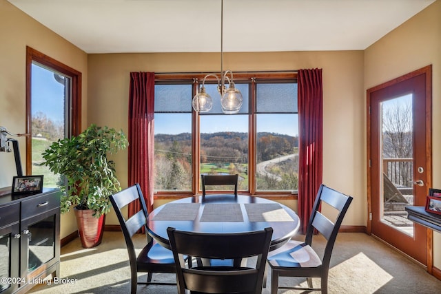 carpeted dining room featuring baseboards and a chandelier