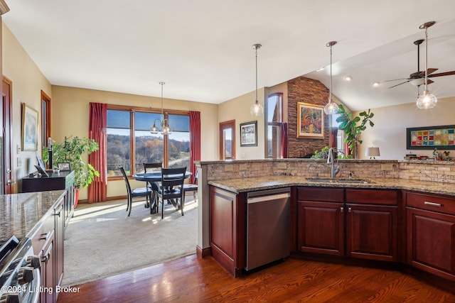 kitchen featuring appliances with stainless steel finishes, a sink, dark wood finished floors, lofted ceiling, and hanging light fixtures