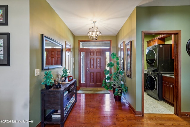 entrance foyer featuring stacked washer / drying machine, a chandelier, light wood-type flooring, and baseboards
