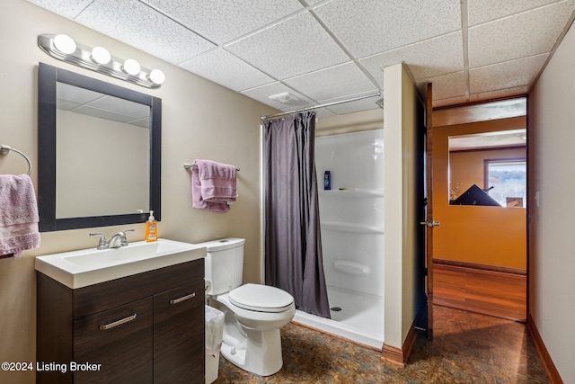 full bathroom with a stall shower, vanity, a paneled ceiling, toilet, and baseboards