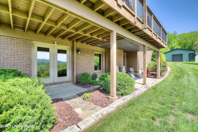 property entrance featuring brick siding, a lawn, french doors, and a patio