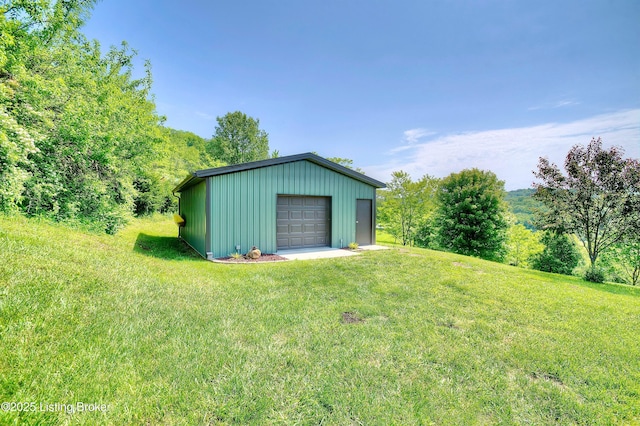 view of green lawn with a garage and an outbuilding