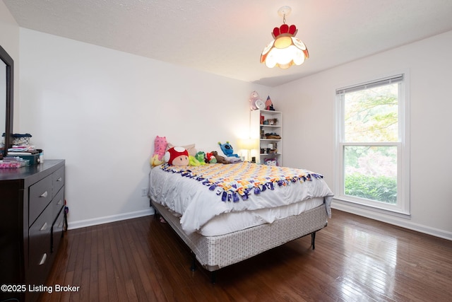 bedroom with dark wood-type flooring and baseboards