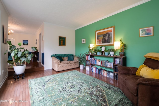 living room featuring crown molding, hardwood / wood-style floors, a chandelier, and baseboards