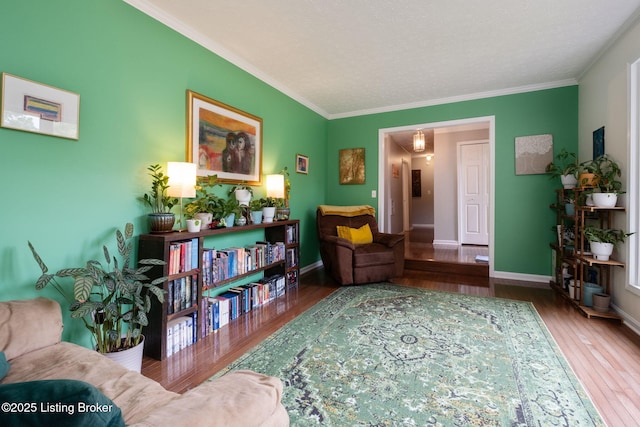 sitting room with wood finished floors, crown molding, and baseboards