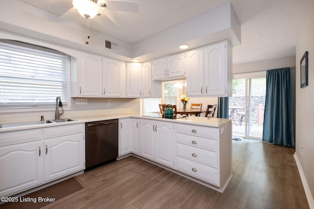 kitchen with dishwashing machine, a sink, a textured ceiling, light wood-style floors, and white cabinetry