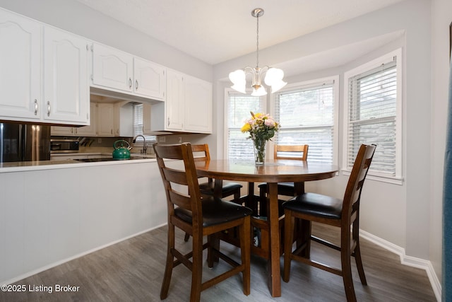 dining space with dark wood finished floors, a chandelier, and baseboards