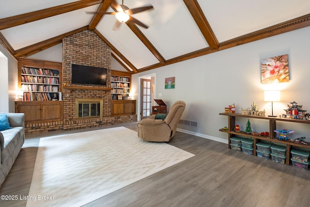 living area with ceiling fan, wood finished floors, baseboards, built in features, and a fireplace