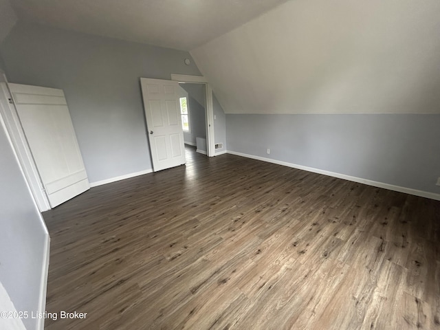 additional living space with lofted ceiling, dark wood finished floors, and baseboards