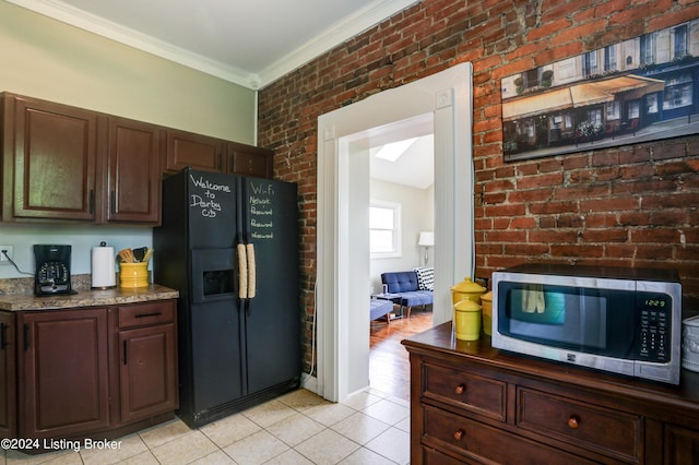 2935 S 3rd St, Louisville, KY 40208 - kitchen with black fridge, stainless steel microwave, crown molding, light tile patterned floors, and brick wall