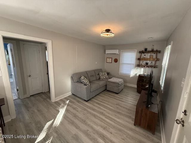 4177 Sherman Ave, Louisville, KY 40213 - living area featuring an AC wall unit, light wood-style floors, and baseboards