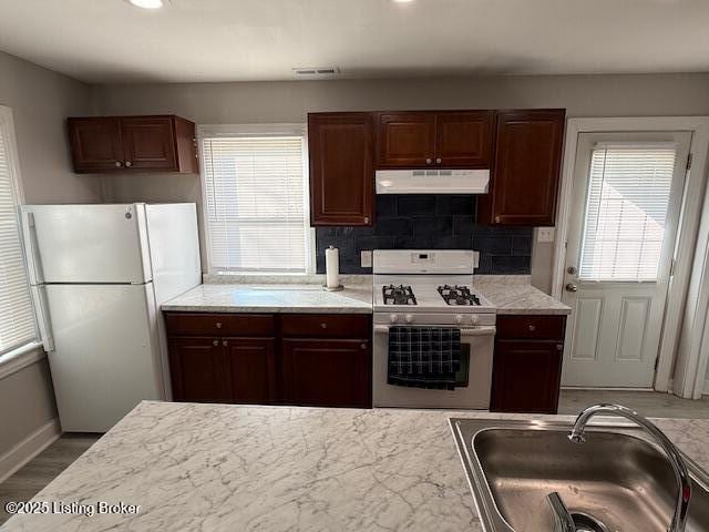 4177 Sherman Ave, Louisville, KY 40213 - kitchen featuring white appliances, a sink, under cabinet range hood, light countertops, and backsplash