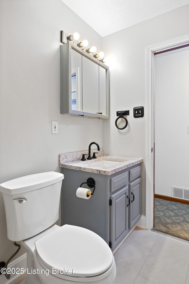 bathroom with toilet, vanity, and tile patterned flooring