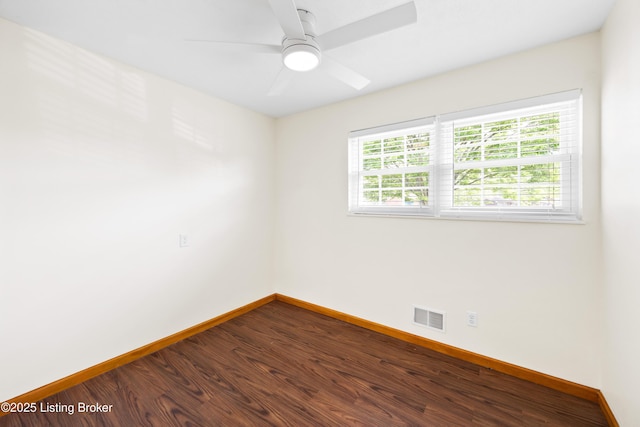 spare room featuring baseboards, dark wood-style floors, and ceiling fan