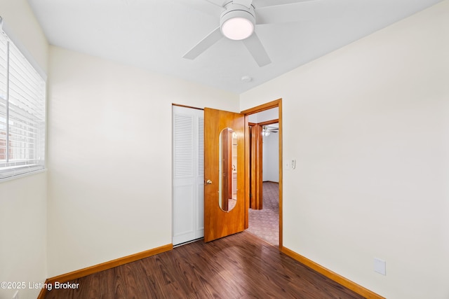unfurnished bedroom with baseboards, multiple windows, and wood finished floors