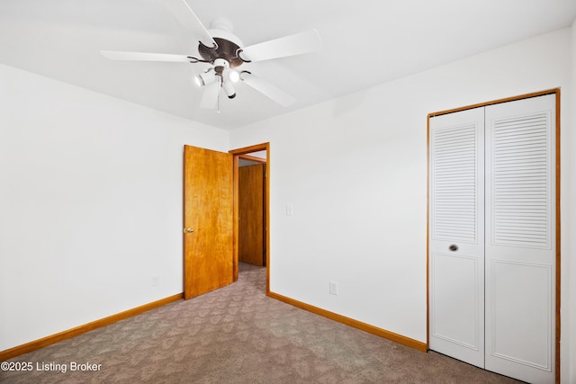 unfurnished bedroom with carpet flooring, baseboards, a closet, and a ceiling fan