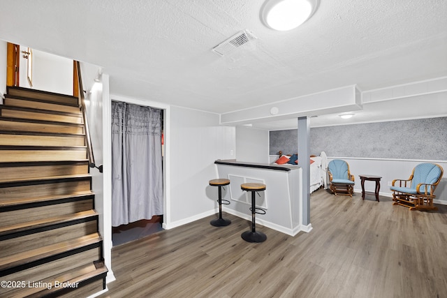 finished basement with wood finished floors, a textured ceiling, stairway, and baseboards