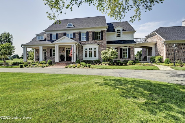 view of front of home with a porch, brick siding, and a front lawn