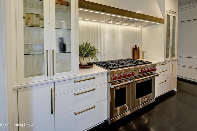kitchen featuring double oven range, backsplash, white cabinetry, glass insert cabinets, and light countertops