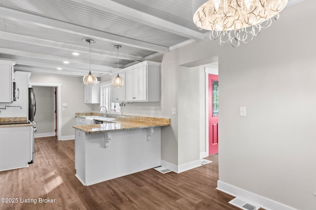 kitchen with baseboards, beamed ceiling, a sink, a peninsula, and white cabinets